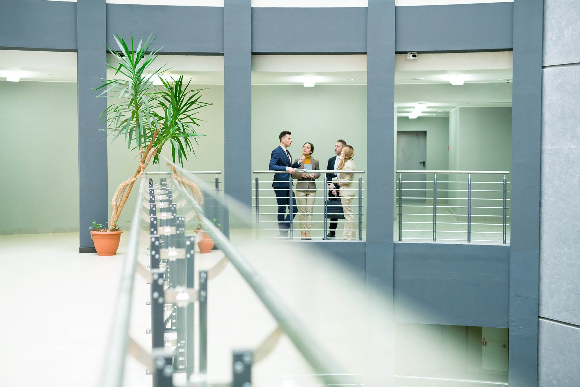 Confident business agent working with potential clients and answering their questions while they standing in office corridor