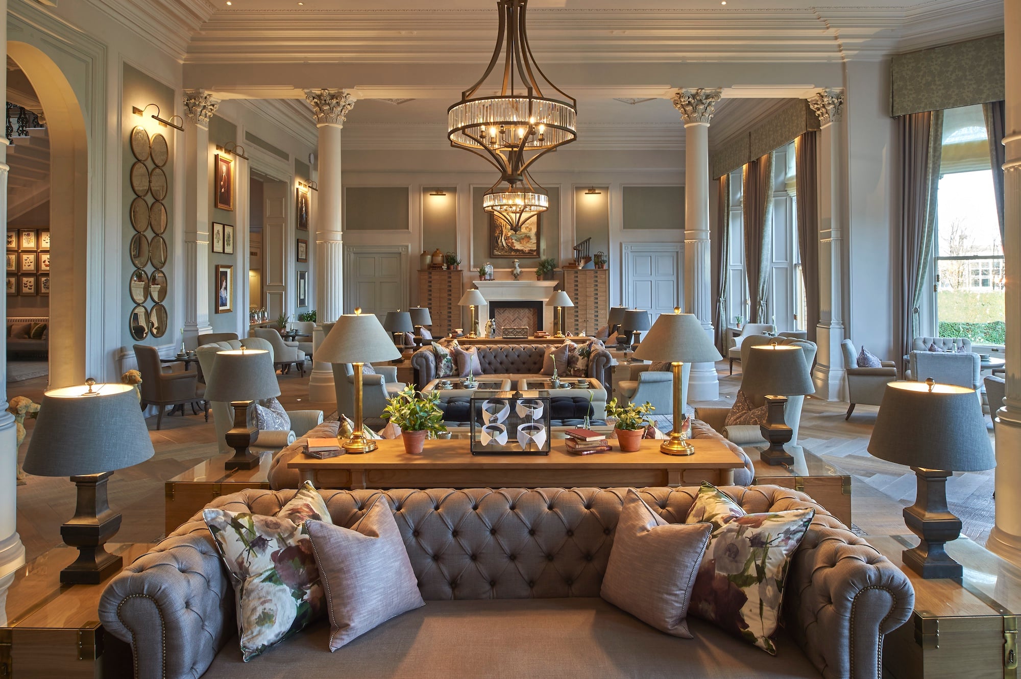 sand toned of luxury furniture of couch, desks, lamps, etc. under chandelier